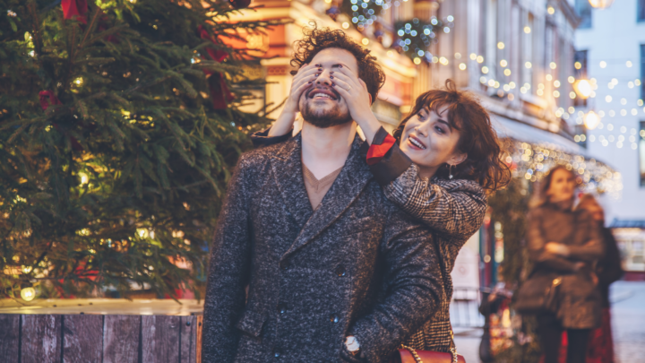 femme qui cache les yeux d'un homme dans une rue décorée pour Noel